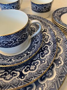 a blue and white dinner set with gold trim