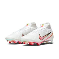 a pair of white and pink nike soccer cleats on a white background,