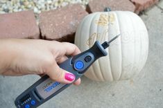 a person holding a tool in their left hand near a pumpkin on the other side