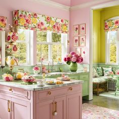 a pink kitchen with green cabinets and floral wallpaper on the walls, along with flowers in vases