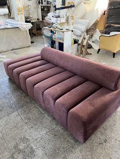 a purple couch sitting on top of a floor next to a pile of furniture in a room