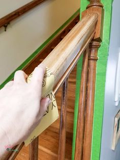 a hand is holding a piece of paper on the bannister rail that has been painted green