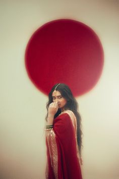 a woman in a red and white dress is standing with her hand on her face