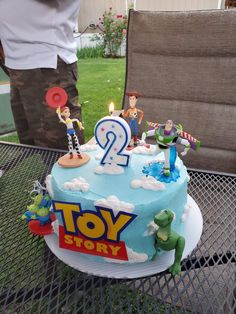 a birthday cake with toy story characters on it sitting on a table in the backyard