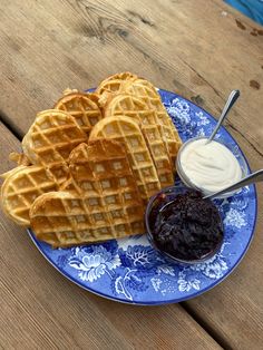 some waffles are on a blue and white plate next to a bowl of jelly