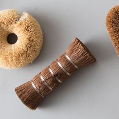 a brown brush sitting on top of a white table next to a donut shaped object