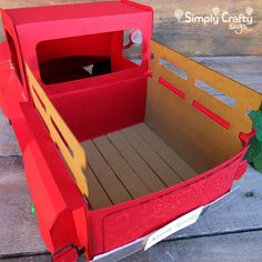 an open cardboard box with a wooden floor and red interior sitting on top of a table