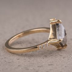 a gold ring with a white diamond on the side and two diamonds in the middle