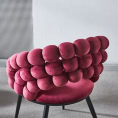 a chair made out of balls sitting on top of a carpeted floor next to a wall