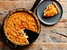 a pie sitting on top of a wooden table next to a plate with a slice missing