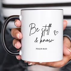 a woman holding a coffee mug with the words be still and know