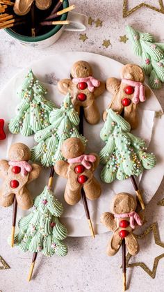 cookies decorated like christmas trees and reindeers on a white plate with gold stars around them