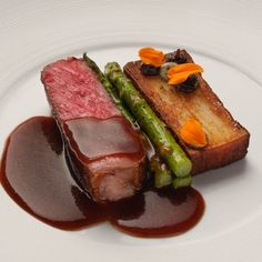 a white plate topped with meat and asparagus