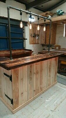 an unfinished kitchen island made out of wood and metal pipes with lights hanging from the ceiling