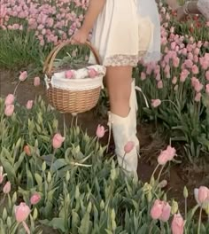 a woman holding a basket in a field of flowers