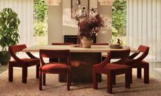 a dining room table with four chairs and a potted plant in the middle on top