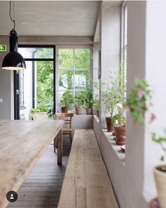 a long wooden table with potted plants on it in the middle of a room