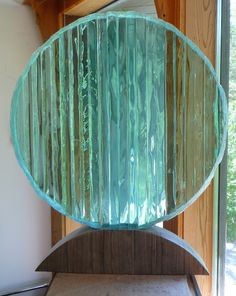 a large glass fish sculpture sitting on top of a wooden table next to a window