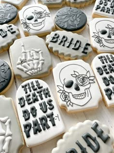 decorated cookies with black and white frosting on a wooden surface, including one for bride and the other for grooms