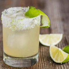 a close up of a drink with lime and sugar on the rim next to sliced limes