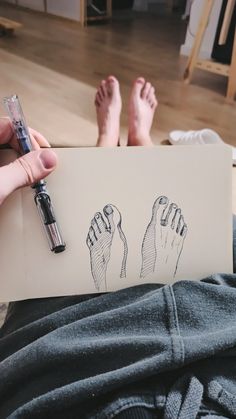 a person holding a piece of paper with two feet on it and a pen in their hand