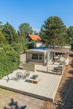 an aerial view of a mobile home on a wooden deck surrounded by trees and shrubs