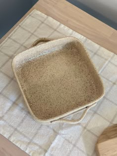 a brown and white dish sitting on top of a table next to a wooden spoon