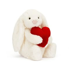 a white stuffed rabbit holding a red heart