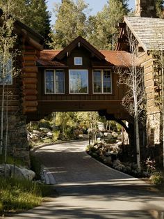 a large wooden house sitting on top of a lush green hillside next to a forest