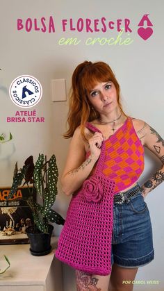 a woman with red hair and tattoos holding a pink crochet tote bag