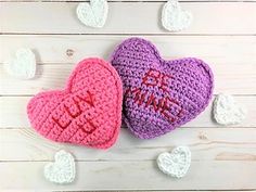 two crocheted hearts sitting next to each other on top of a wooden table