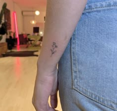 a small flower tattoo on the left arm