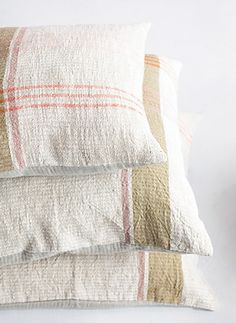 three pillows stacked on top of each other in front of a white wall with a clock