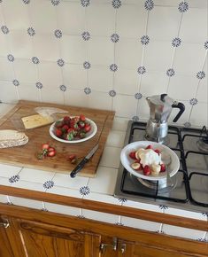 a wooden cutting board sitting on top of a counter next to a bowl of fruit