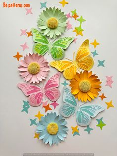 paper flowers and butterflies are arranged on a white surface