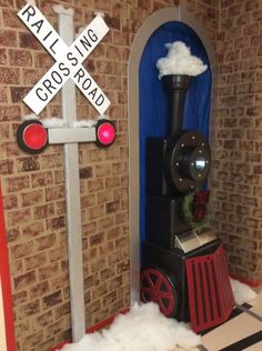 there is a fake train and railroad crossing sign in the room with snow on the floor