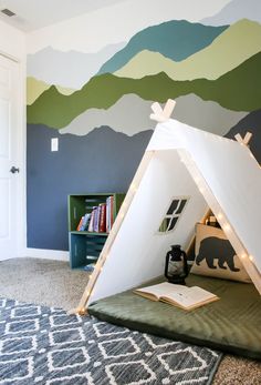 a teepee tent in the corner of a room with mountains painted on the wall