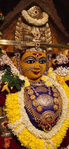 an elaborately decorated mask is displayed in front of flowers