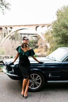 a woman standing next to a black car