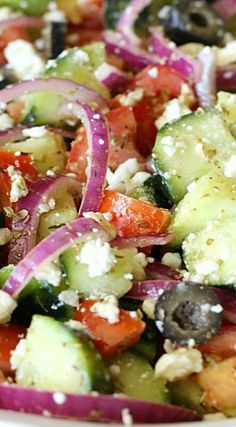 a salad with cucumbers, tomatoes, onions and olives