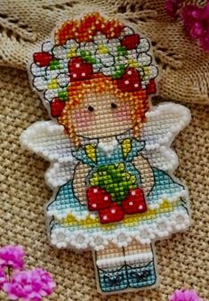 a cross stitch angel ornament with pink flowers