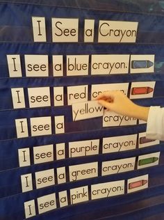 i see a crayon word wall with words on it and hand pointing at the letters