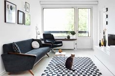 a black and white living room with a cat sitting on the floor