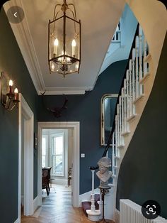 a hallway with blue walls and wooden floors, chandelier hanging from the ceiling