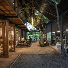 the inside of a building with people sitting at tables and reading books on benches under a tree