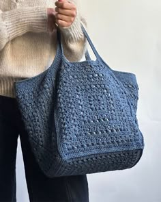 a woman holding a crocheted blue purse