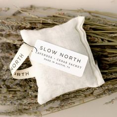 a pillow that is sitting on top of some dried lavenders with the words slow north printed on it