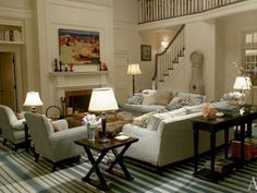 a living room filled with furniture and a fire place under a stair case next to a staircase