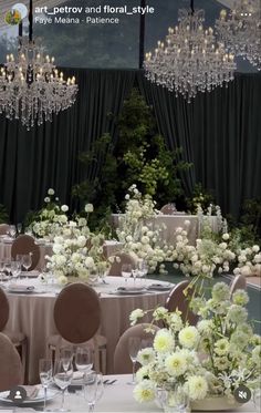 a table set up for a formal function with chandeliers and flowers in vases