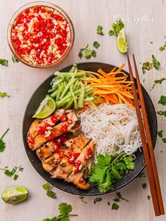 a plate filled with meat and vegetables next to chopsticks on a white table